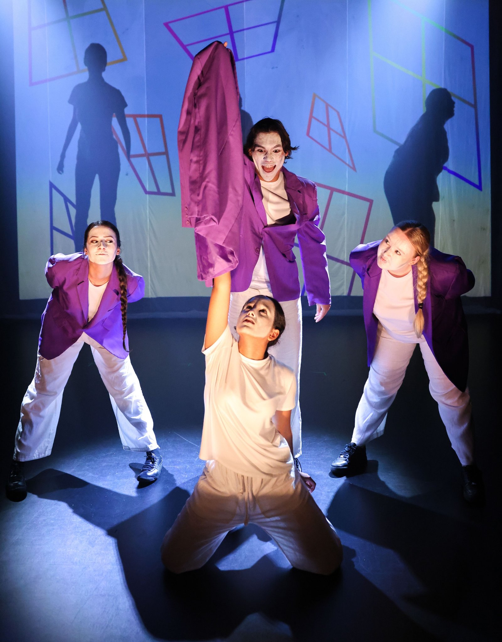 Theatre performers in purple and white costumes